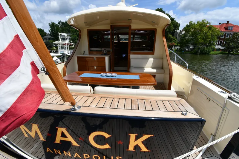 Mack Yacht Photos Pics 2020 Palm Beach Motor Yachts PB52, elegant deck view with seating and table, docked by water.