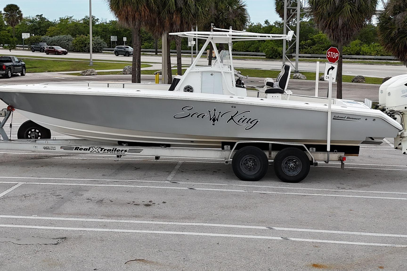 2002 Island Runner 31 boat on trailer, labeled "Sea King," parked near palm trees.