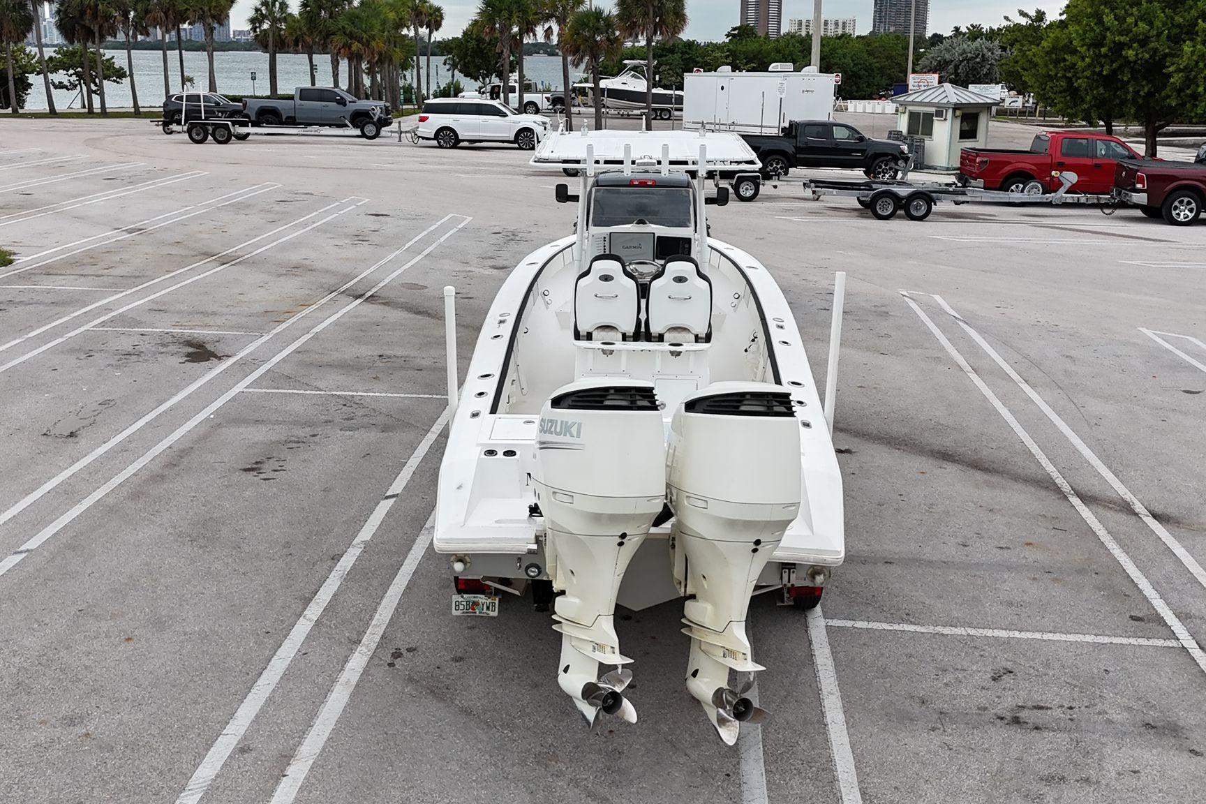 2002 Island Runner 31 boat with dual Suzuki engines in a parking lot near water.