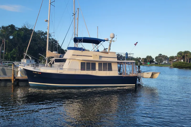 Make Me Smile Yacht Photos Pics 2006 Mainship 40 Trawler docked on calm water, surrounded by lush greenery.
