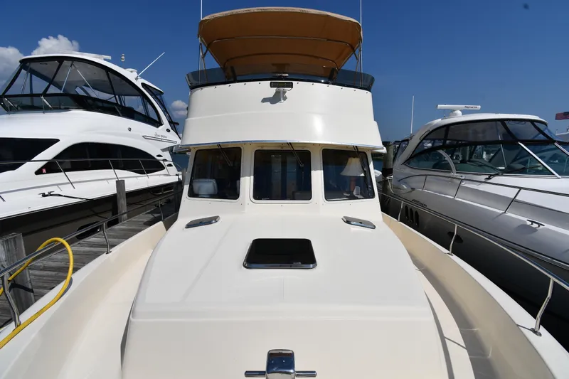 Make Me Smile Yacht Photos Pics 2006 Mainship 40 Trawler docked between two yachts under a clear blue sky.