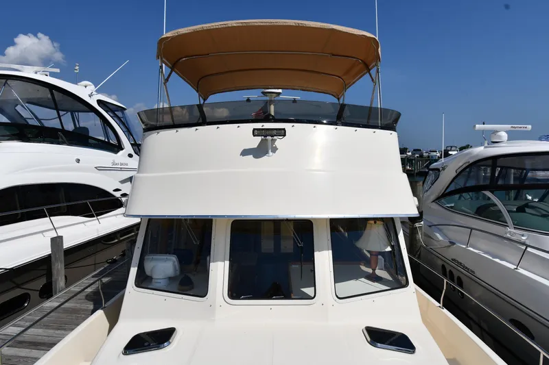 Make Me Smile Yacht Photos Pics 2006 Mainship 40 Trawler docked between two boats under a clear blue sky.