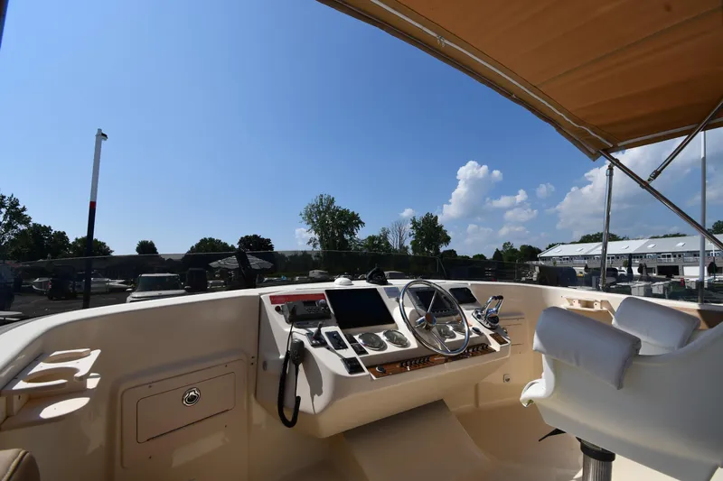 Make Me Smile Yacht Photos Pics 2006 Mainship 40 Trawler helm with steering wheel, controls, and seating under a canopy.