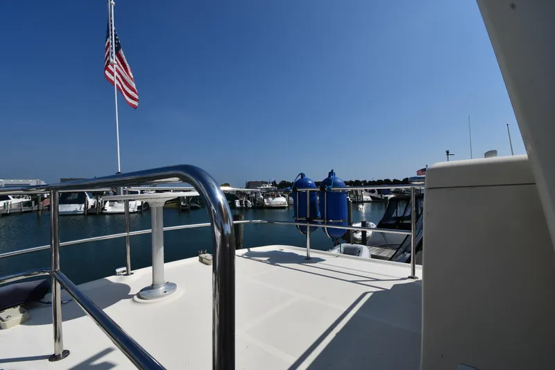 Make Me Smile Yacht Photos Pics 2006 Mainship 40 Trawler deck with American flag, docked at marina under clear blue sky.