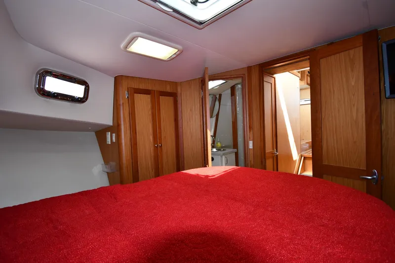 Make Me Smile Yacht Photos Pics Interior of 2006 Mainship 40 Trawler with red bedding and wooden cabinetry.