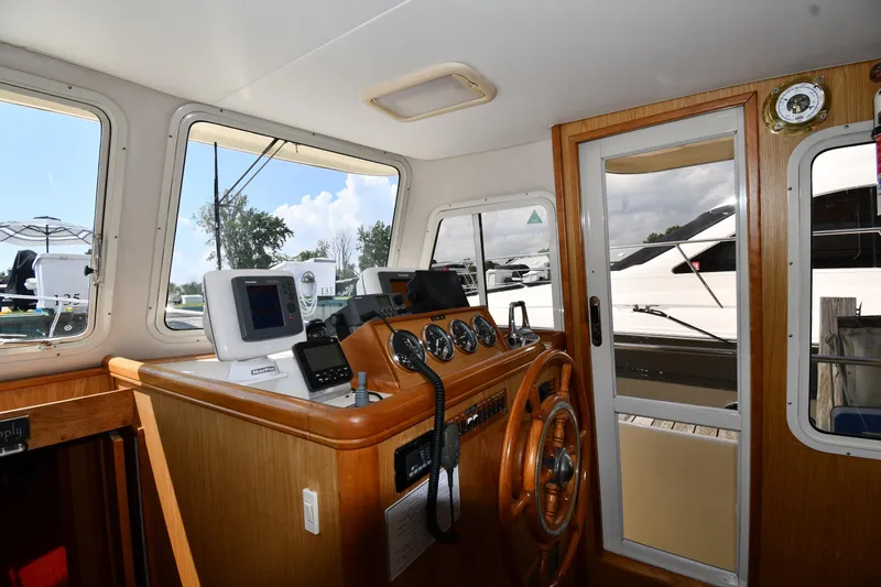 Make Me Smile Yacht Photos Pics Interior helm of 2006 Mainship 40 Trawler with navigation equipment and wooden steering wheel.