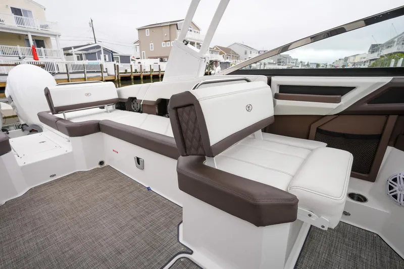 Plane To Sea Yacht Photos Pics 2022 Cobalt R8 boat interior with white and brown seating, docked near waterfront homes.
