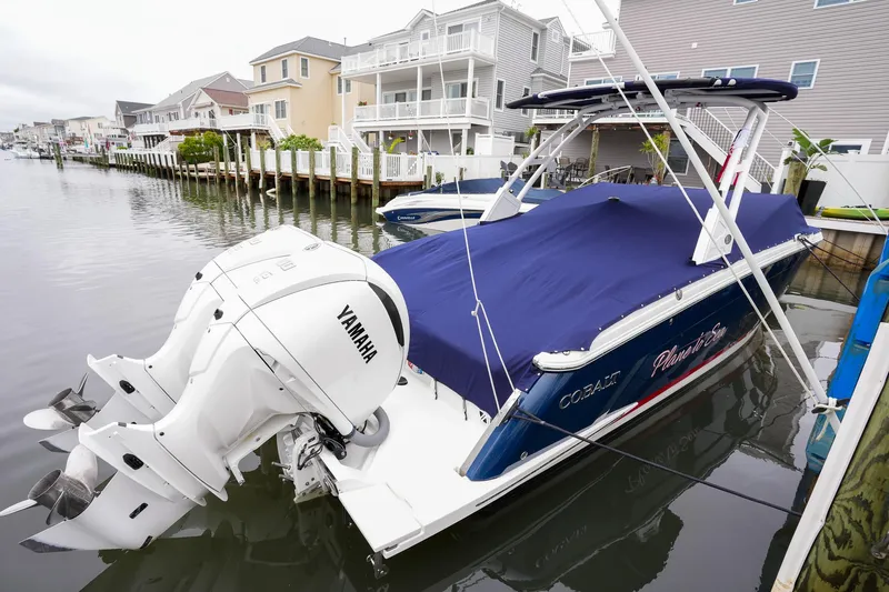 Plane To Sea Yacht Photos Pics 2022 Cobalt R8 boat docked, covered with blue tarp, featuring Yamaha outboard motor.