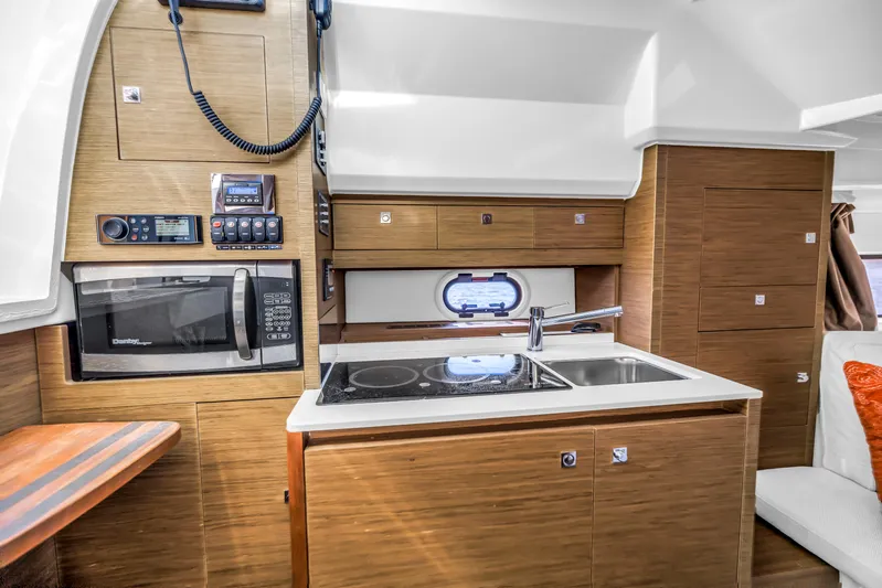  Yacht Photos Pics Modern kitchen area in a 2019 Jeanneau Leader 10.5 CC boat, featuring wood cabinetry and appliances.