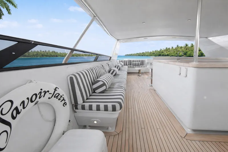 Savoir-faire Yacht Photos Pics Luxurious Ocean Alexander 120 Megayacht deck with striped seating, ocean view, and tropical backdrop.