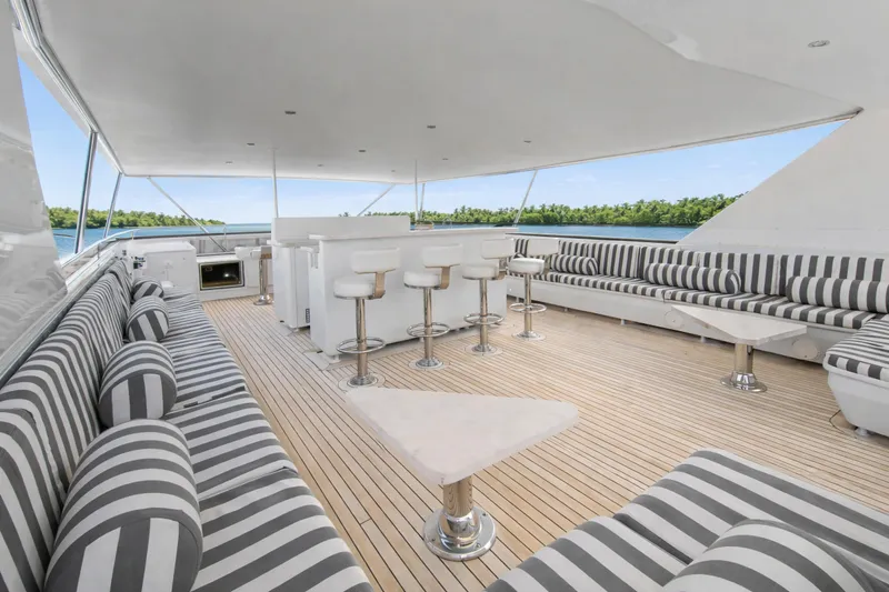 Savoir-faire Yacht Photos Pics Luxurious Ocean Alexander 120 Megayacht deck with striped seating, bar stools, and scenic ocean view.
