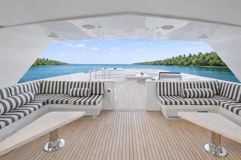 Savoir-faire Yacht Photos Pics Luxurious Ocean Alexander 120 Megayacht deck with striped seating, ocean view, and tropical backdrop.