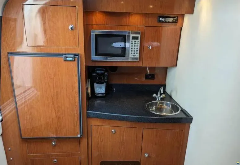  Yacht Photos Pics 2008 Regal Commodore 3760 IO yacht kitchenette with microwave, sink, and wooden cabinetry.
