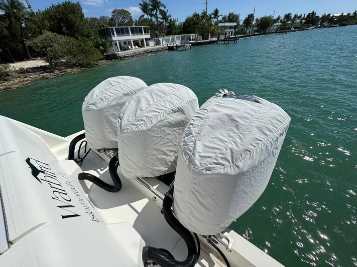 Warbird Yacht Photos Pics 2014 SeaVee 390B Center Console with covered outboard motors on a sunny waterfront.