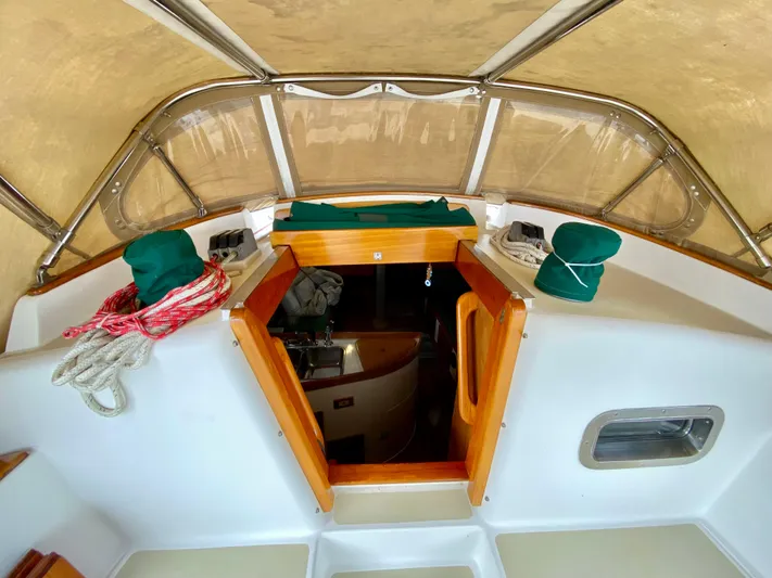 Private Idaho Yacht Photos Pics 1993 Cabo Rico 34 sailboat cockpit with wooden hatch, ropes, and green covers.