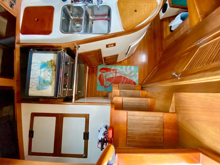 Private Idaho Yacht Photos Pics Interior of 1993 Cabo Rico 34 sailboat with wooden cabinetry and compact kitchen area.