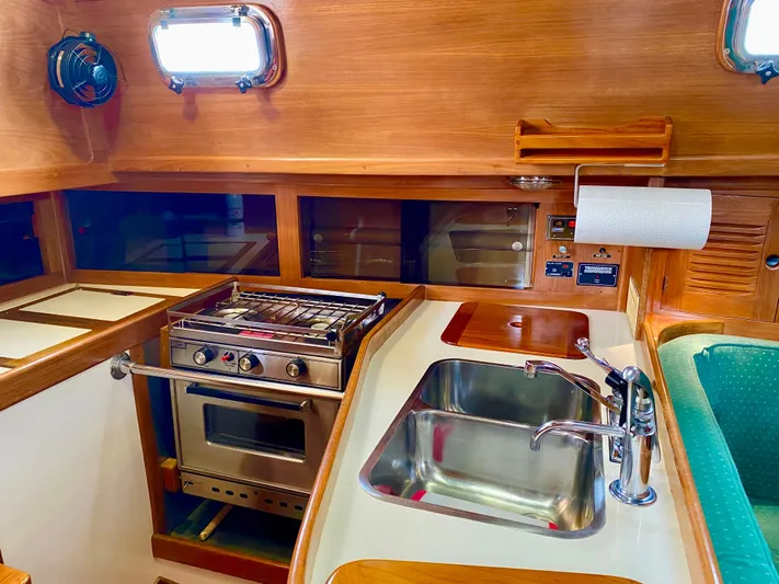 Private Idaho Yacht Photos Pics 1993 Cabo Rico 34 yacht kitchen with stove, sink, and wooden cabinetry.