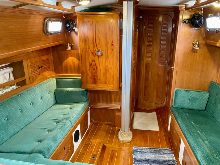 Private Idaho Yacht Photos Pics Interior of 1993 Cabo Rico 34 sailboat with wooden paneling and green seating.