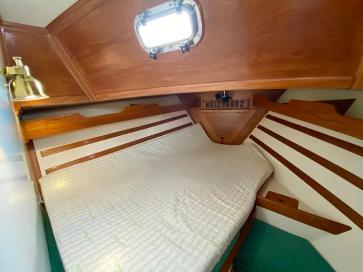 Private Idaho Yacht Photos Pics Cabin interior of 1993 Cabo Rico 34 sailboat with wooden accents and a cozy bed.