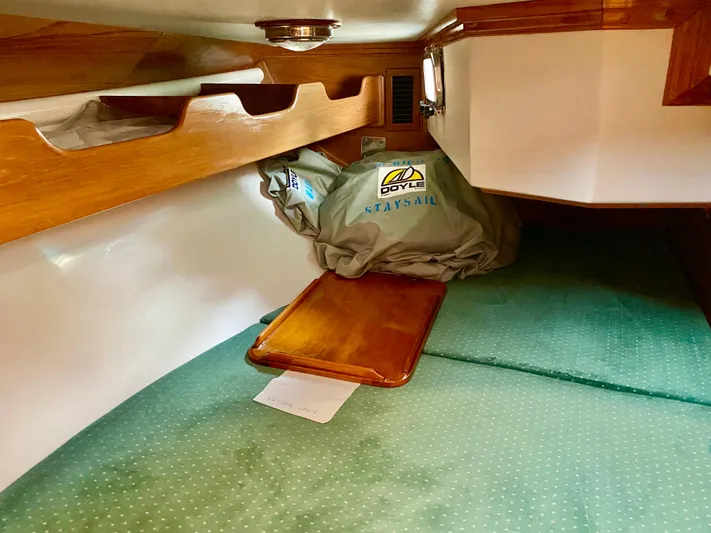 Private Idaho Yacht Photos Pics Cabo Rico 34 sailboat interior, 1993 model, featuring wooden shelves and green bedding.