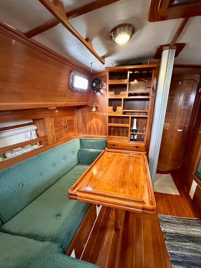 Private Idaho Yacht Photos Pics Interior of 1993 Cabo Rico 34 sailboat with wooden table and green seating.