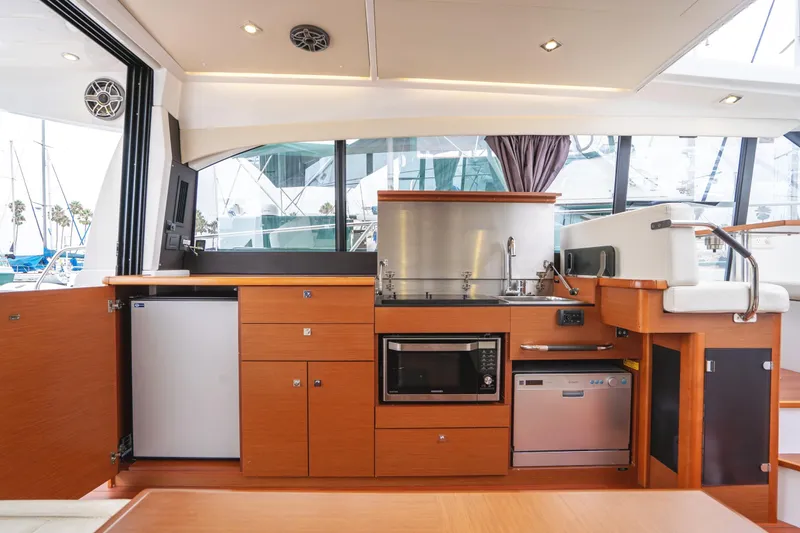 La Sirena Yacht Photos Pics 2014 Jeanneau NC 14 yacht interior kitchen with modern appliances and sleek wood cabinetry.
