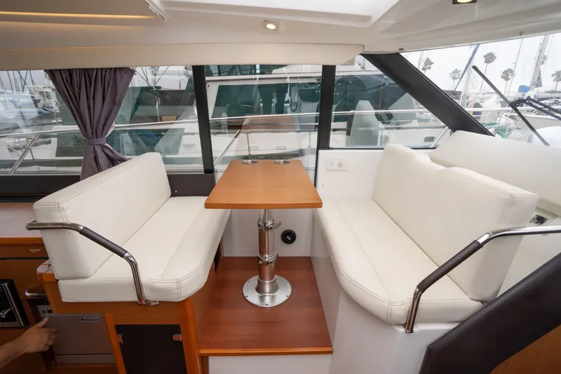 La Sirena Yacht Photos Pics Interior of 2014 Jeanneau NC 14 yacht with white seating and wooden table.