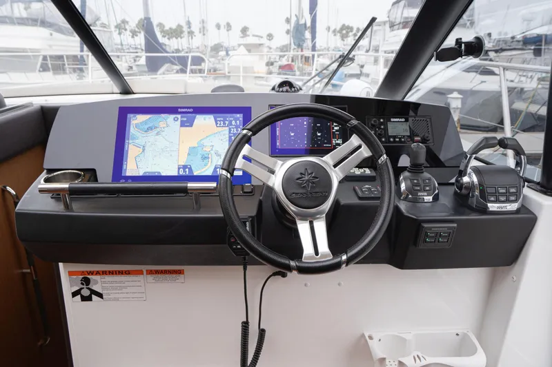 La Sirena Yacht Photos Pics 2014 Jeanneau NC 14 helm with navigation screens and controls in a marina setting.