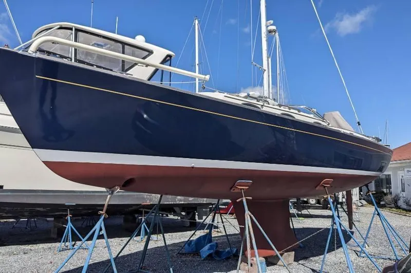  Yacht Photos Pics 2006 Alerion Express 38 sailboat on stands, blue hull, red bottom, clear sky background.