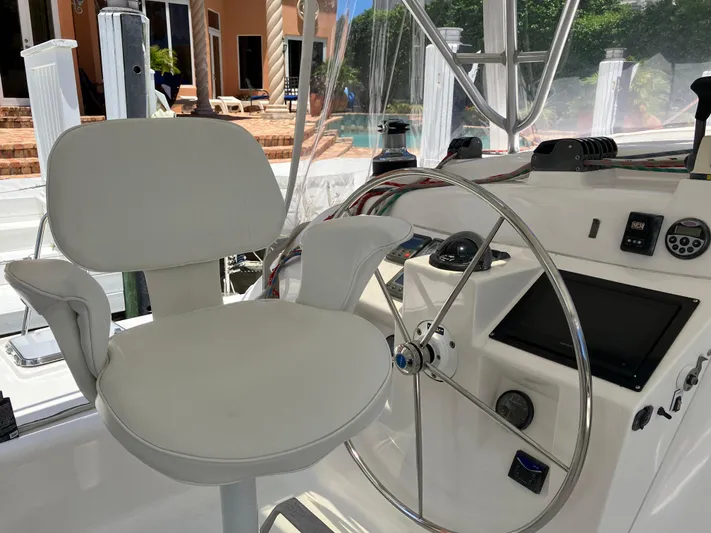 Bel Tempo Yacht Photos Pics Helm station of 2008 Manta 42 MkIV catamaran with white captain's chair and steering wheel.