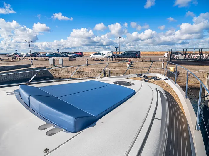  Yacht Photos Pics 2008 Princess V65 yacht deck with blue sunpad, docked under a bright blue sky.