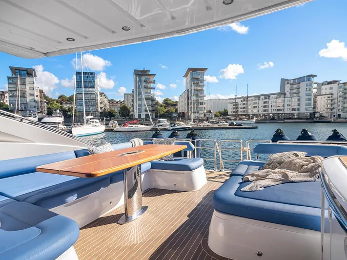  Yacht Photos Pics Luxurious 2008 Princess V65 yacht deck with blue seating, wooden table, and waterfront view.