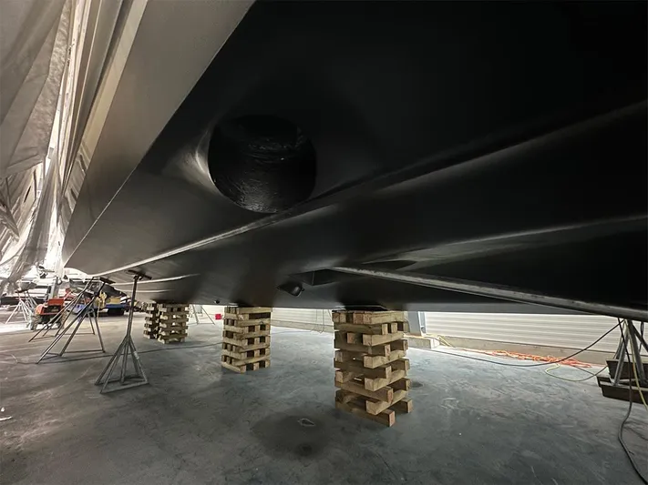  Yacht Photos Pics Underside of 2008 Princess V65 yacht on wooden blocks in a maintenance facility.