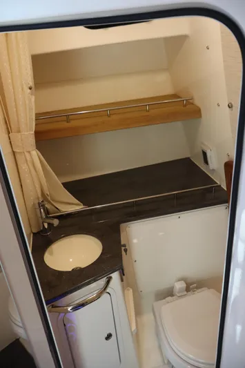  Yacht Photos Pics 2023 Boston Whaler 350 Realm boat bathroom with sink, toilet, and storage shelf.