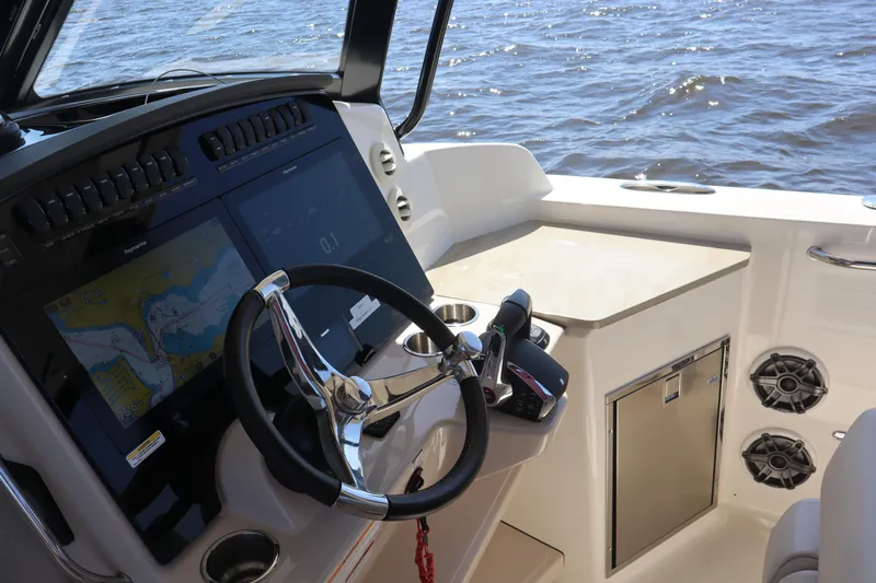  Yacht Photos Pics 2023 Boston Whaler 350 Realm helm with navigation screens and steering wheel, overlooking the water.