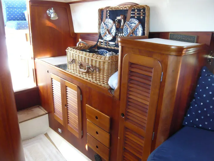 Courage Yacht Photos Pics Interior of 1998 Hinckley 36 Classic yacht with wooden cabinetry and wicker picnic basket.