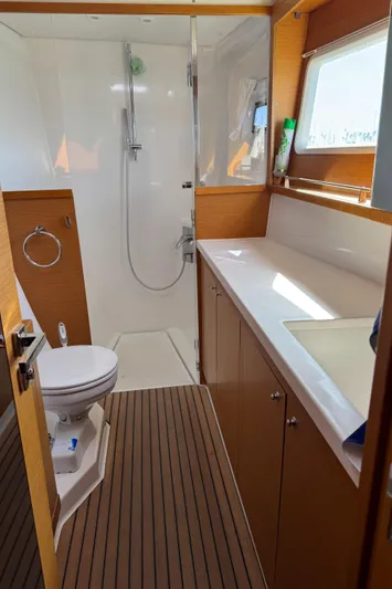  Yacht Photos Pics 2017 Lagoon 450 F yacht bathroom with shower, toilet, and wooden cabinetry.