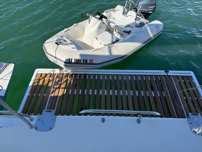  Yacht Photos Pics Lagoon 450 F yacht with a small boat docked on calm water, 2017 model.