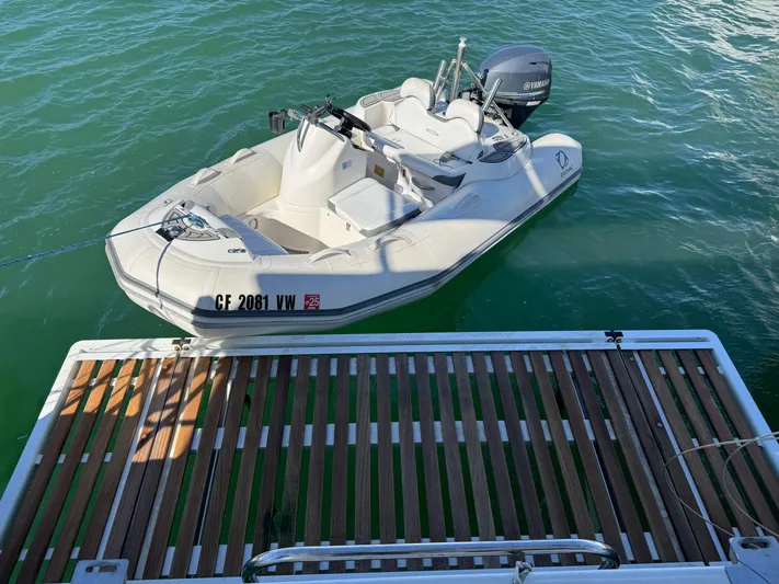  Yacht Photos Pics A small white motorboat docked near a Lagoon 450 F catamaran, floating on calm green water.