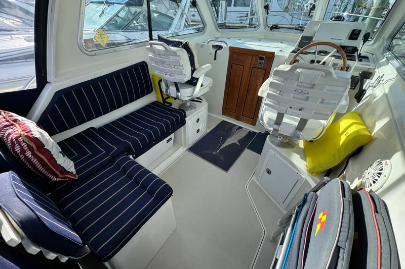  Yacht Photos Pics Interior of a 2006 BackCove 29 boat with striped seating and wooden helm.