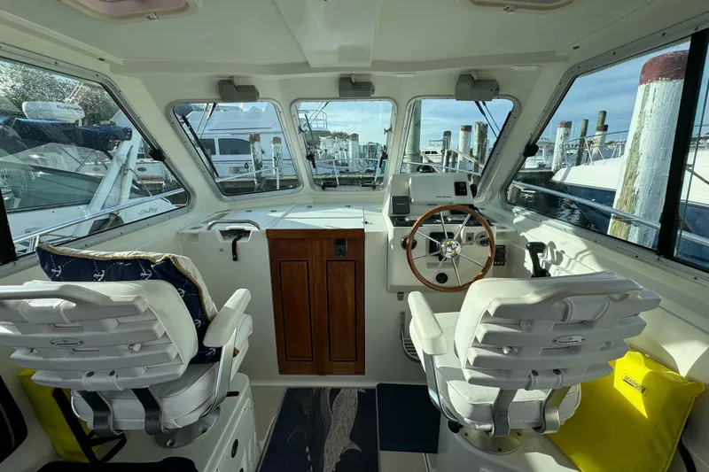  Yacht Photos Pics Interior of a 2006 BackCove 29 boat with helm, steering wheel, and two white seats.