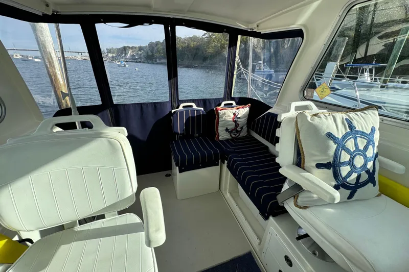  Yacht Photos Pics Interior of a 2006 BackCove 29 boat with nautical-themed cushions and scenic water view.