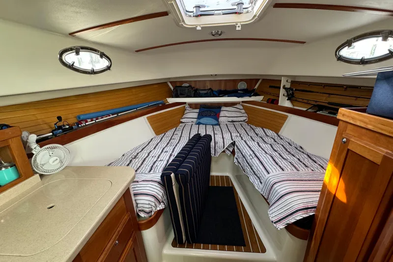  Yacht Photos Pics 2006 BackCove 29 boat interior with cozy striped bedding and wooden accents.