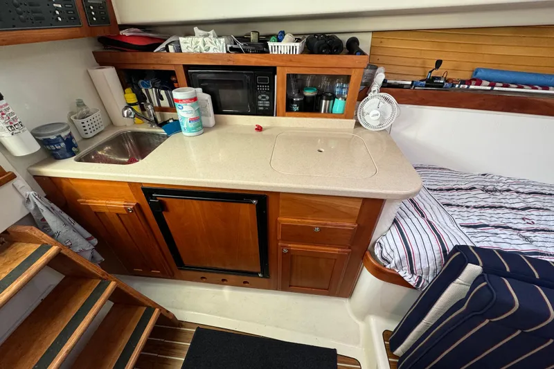  Yacht Photos Pics 2006 BackCove 29 interior with kitchenette, sink, microwave, and bed.