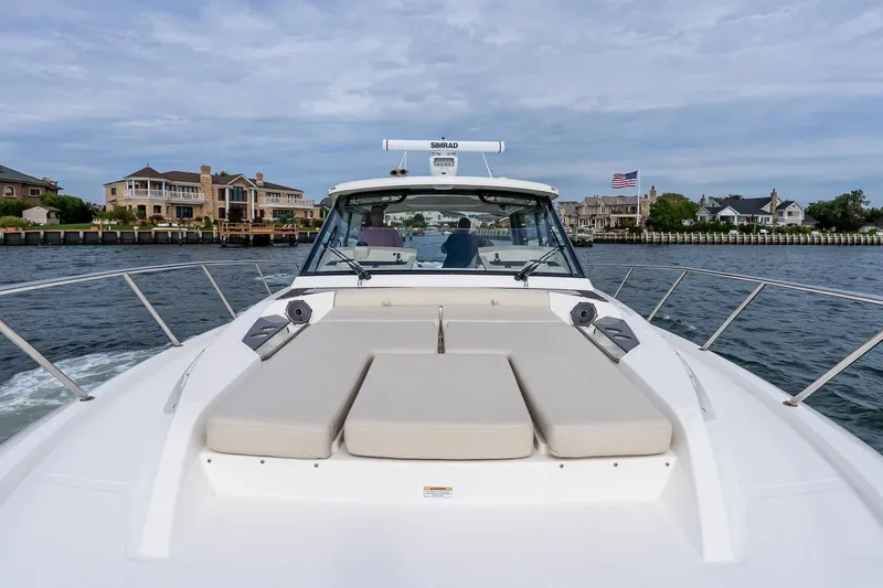  Yacht Photos Pics 2024 Boston Whaler 405 Conquest cruising near waterfront homes, showcasing luxury and comfort.