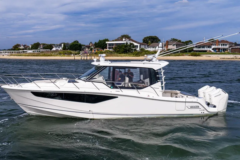  Yacht Photos Pics 2024 Boston Whaler 405 Conquest cruising on water near coastal homes.