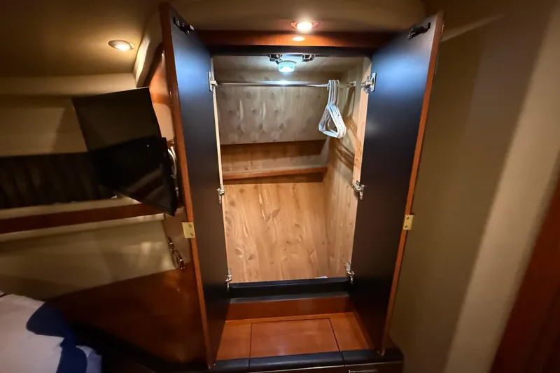 Notorious Yacht Photos Pics Open wooden closet inside 2003 Sea Ray 460 Sundancer yacht, featuring hangers and interior lighting.