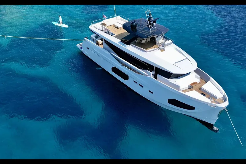  Yacht Photos Pics 2023 Numarine 22 XP yacht anchored in clear blue water, with a paddleboard nearby.