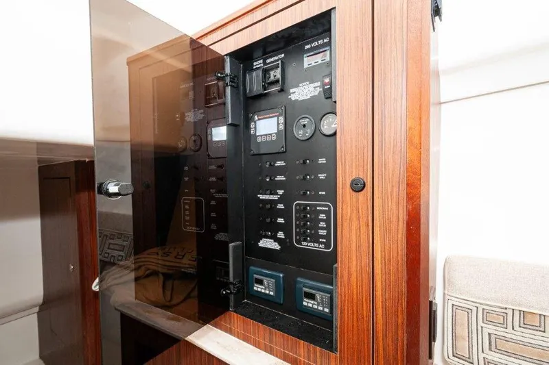 Silver Lining Yacht Photos Pics Electrical panel inside 2023 Pursuit DC 365 Dual Console boat, featuring wood finish and control switches.