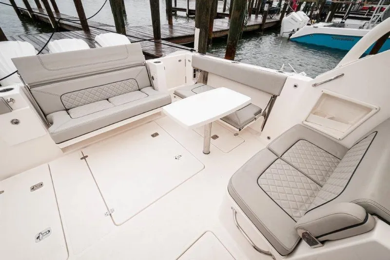 Silver Lining Yacht Photos Pics 2023 Pursuit DC 365 Dual Console boat interior with cushioned seating and table.